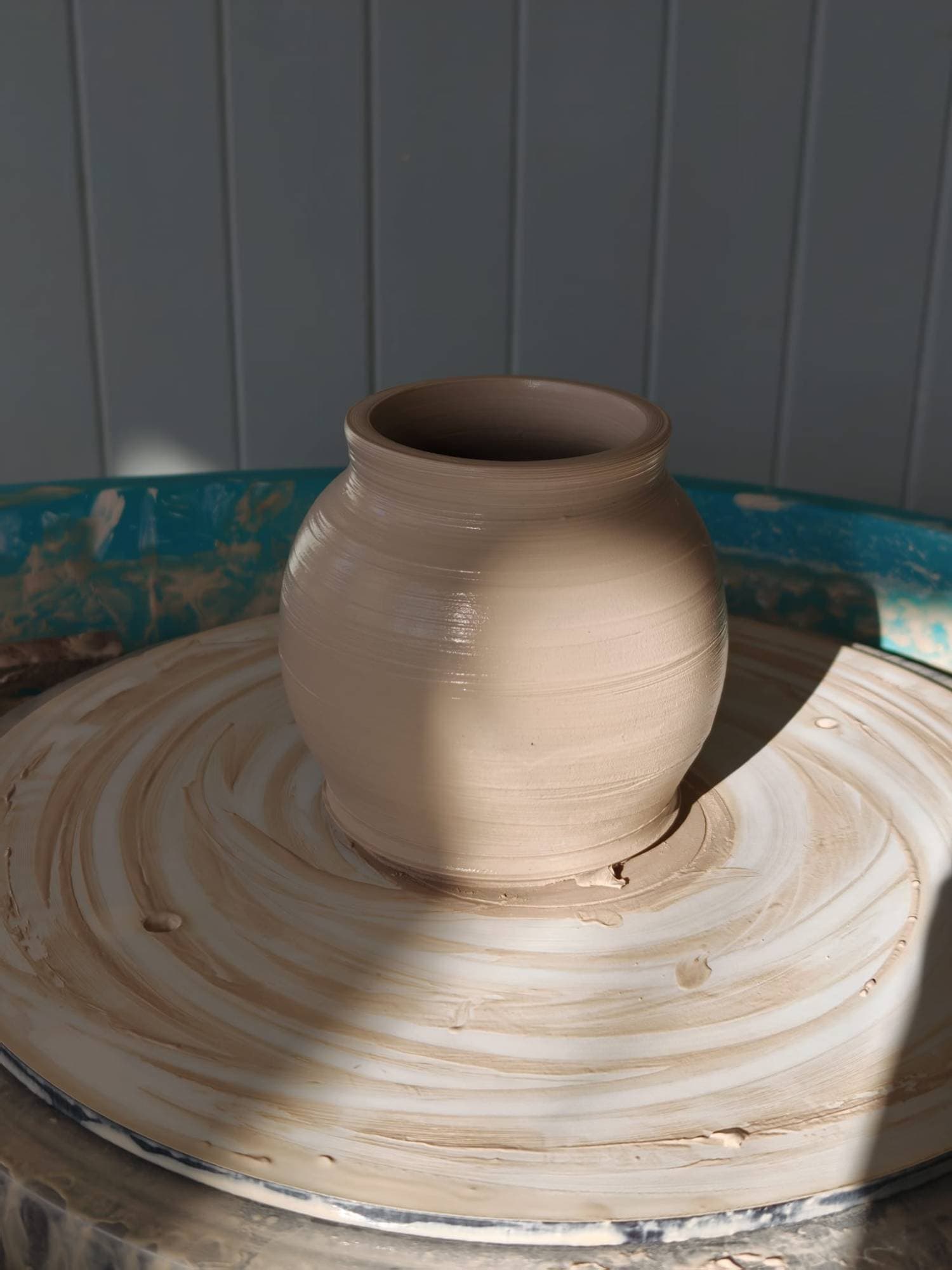 A round pot freshly thrown, still on the wheel